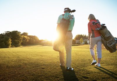 Shot of a retired couple walking across a golf green
