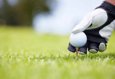 Golf ball being carefully balanced on a golf tee